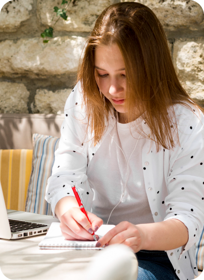 University student writing notes while working on a business capstone project with expert academic support in UK.